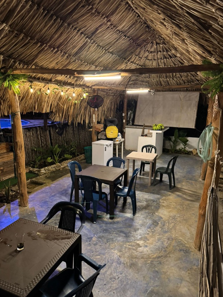 Salón comunal con techo de palma y mesas