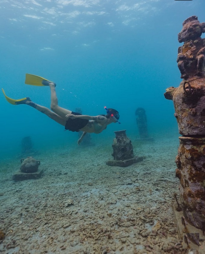 Persona haciendo snorkel sobre figuras bajo el agua